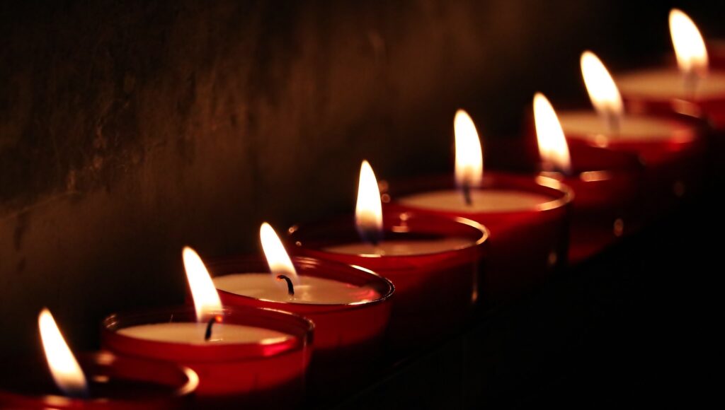 A row of candle flames illuminating a contemplative space